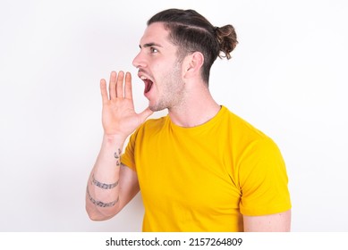 Young caucasian man wearing yellow t-shirt over white background look empty space holding hand near her face and screaming or calling someone. - Shutterstock ID 2157264809