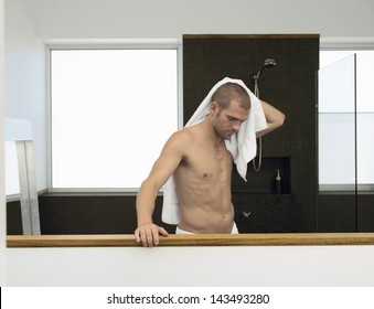 Young Caucasian man wiping himself with a towel after bath
