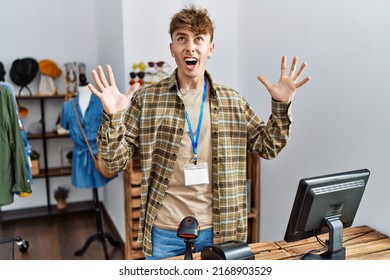 Young caucasian man working as manager at retail boutique crazy and mad shouting and yelling with aggressive expression and arms raised. frustration concept. 