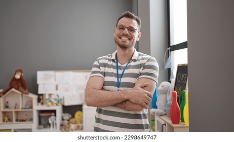 Young caucasian man working as teacher smiling with crossed arms at kindergarten - Shutterstock ID 2298649747