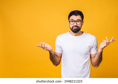 Young caucasian mistaken confused bearded man spreading hands oops gesture isolated on yellow background studio portrait People lifestyle concept