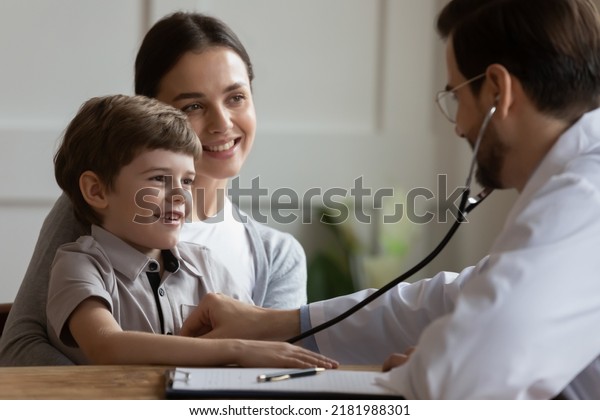 Young Caucasian mom with little son visit\
pediatrician do checkup examination in hospital. Male doctor or GP\
listen to small boy patient heart chest at consultation in clinic.\
Healthcare concept.