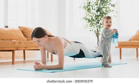 Young caucasian mother keeping fit shaping doing sport exercises at home, losing weight after labor and baby delivery. Postnatal period training with small kid toddler infant
