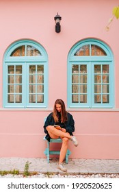 Young Caucasian Northern European Woman Sitting While Reading A Book In Her Colorful Summer Home