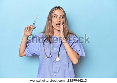 Young caucasian nurse in blue studio is saying a secret hot braking news and looking aside