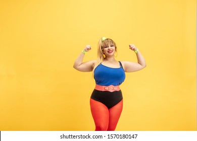 Young Caucasian Plus Size Female Model's Training On Yellow Background. Stylish Woman In Bright Clothes. Copyspace. Concept Of Sport, Healthy Lifestyle, Body Positive, Fashion. Girl Power And Strenght