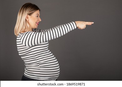 Young caucasian pregnant woman in third trimester posing in front of grey background