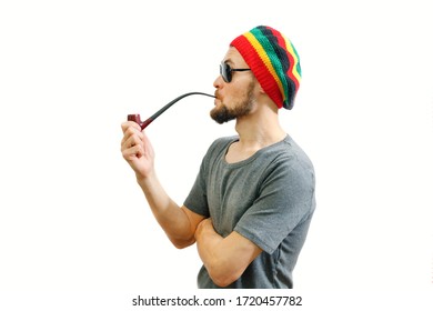 Young Caucasian Rasta Man In Jamaica Hat, Sunglasses And Grey T-shirt On White Background With Smoke Pipe In Hand