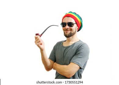 Young Caucasian Rasta Man In Jamaica Hat, Sunglasses And Grey T-shirt On White Background With Smoke Pipe In Hand