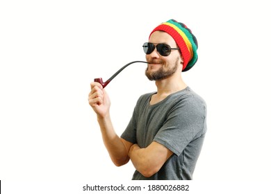 Young Caucasian Rasta Man In Jamaica Hat, Sunglasses And Grey T-shirt On White Background With Smoke Pipe In Hand.