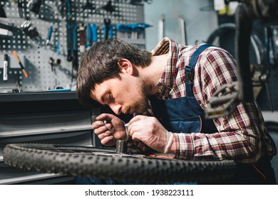 Young Caucasian Repairman Repairing Mountain Bike Wheel In Bike Shop Workshop. Fixing Bicycle. Caring For You Wheels. Man Mechanic Working In Garage. Worker Fixing Cycle Gear. Small Business Theme.