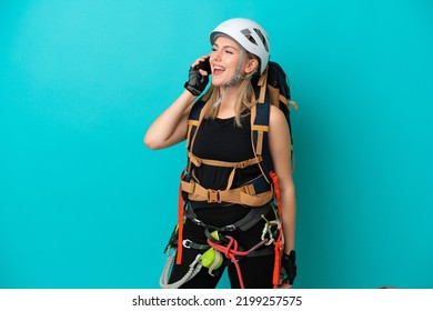 Young Caucasian Rock Climber Woman Isolated On Blue Background Keeping A Conversation With The Mobile Phone