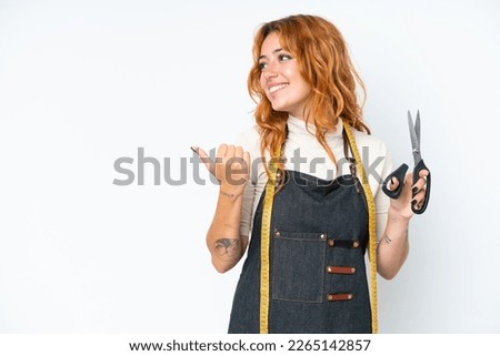Young caucasian seamstress woman isolated on white background pointing to the side to present a product