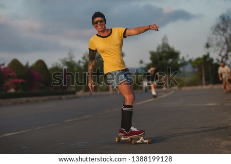 Similar – Young man riding on skate and holding surfboard