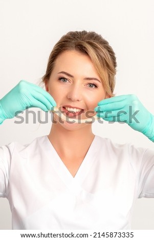 Young caucasian smiling female beautician holding wax for depilation over white background. Yellow sugar paste in hands master of depilation. Epilation concept
