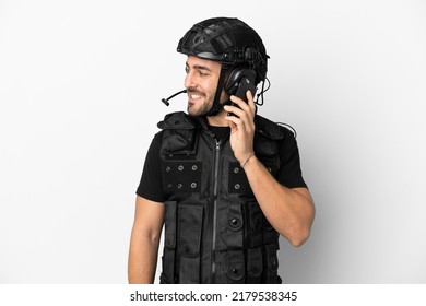 Young Caucasian Swat Isolated On White Background Keeping A Conversation With The Mobile Phone With Someone