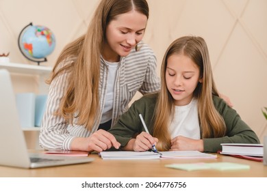 Young Caucasian Teacher Mother Tutor Babysitter Nanny Helping Her Daughter Schoolgirl Student With Homework, School Project, Preparing For Test Exam At Home.