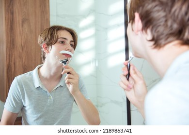 Young Caucasian Teen Boy Shaving Beard In Bathroom