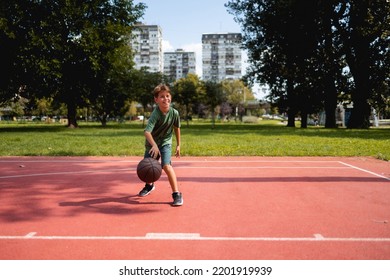 Young Caucasian Teenage Boy Playing Basketball.  He Is Wearing Summer Outfit With Shorts And T-shirt.