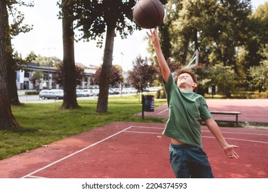 Young Caucasian Teenage Boy Playing Basketball.  He Is Wearing Summer Outfit With Shorts And T-shirt.