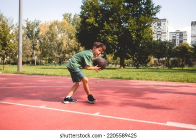 Young Caucasian Teenage Boy Playing Basketball.  He Is Wearing Summer Outfit With Shorts And T-shirt.