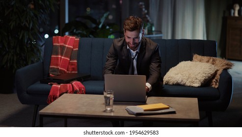 Young Caucasian Tired Arriving Home Returning From Office Late At Night. Unhappy Exhausted Businessman Opening Laptop To Finish Project Before Deadline.