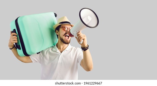 Young Caucasian Tourist Man In Summer Hat With Luggage Suitcase On Shoulder Screaming On Megaphone Advertising Great Tour Agency Offer, Sale Discount. Studio Portrait With Copy Space