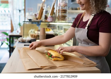 Young caucasian waitress packing prepared sandwich in commercial kitchen - Powered by Shutterstock