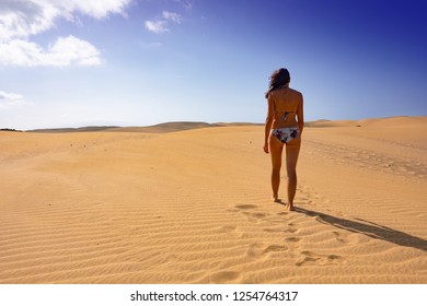 Young Caucasian Woman In A Biking Is Walking Along The Dunes Of Maspalomas, Gran Canaria