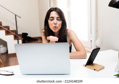 Young Caucasian Woman Blowing A Kiss Goodbye During Video Call With A Friend At Home.