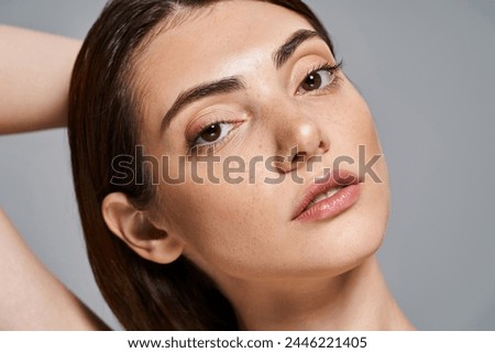 A young caucasian woman with brunette hair poses gracefully in a clean white shirt, exuding elegance and simplicity.