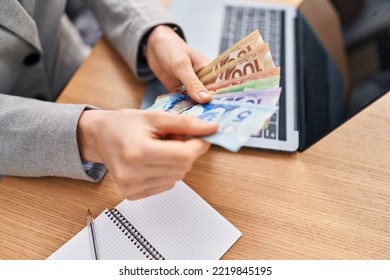Young caucasian woman business worker using laptop counting canada dollars at office