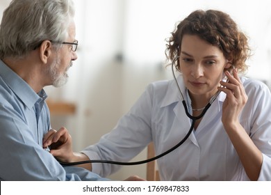 Young Caucasian Woman Cardiologist Doctor Use Stethoscope Do Regular Checkup Examine Mature Male Patient, Female Nurse Listen To Heart Rate Of Ill Senior Man In Hospital, Elderly Healthcare Concept