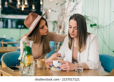 young caucasian woman comforts her friend in cafe during coffee break - Powered by Shutterstock