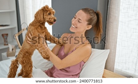 Young caucasian woman with dog playing sitting on the bed at bedroom