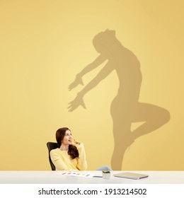 Young Caucasian Woman Dreaming About Future In Big Sport During Her Work In Office. Shadow, Silhouette Of Female Dancer On The Wall. Becoming A Legend. Inspiration, Aspiration. Copyspace.