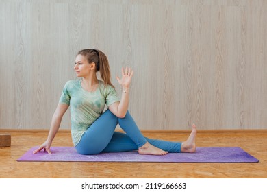 Young caucasian woman dressed in a blue leggins and t-shirt doing yoga asanas at home. Fitness and healthy lifestyle concept.