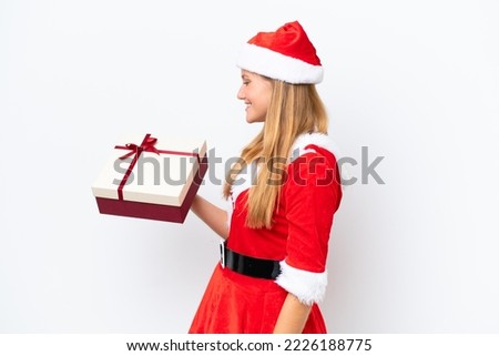Young caucasian woman dressed as mama noel holding gift isolated on white background with happy expression