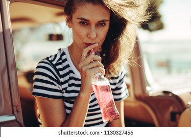 Young Caucasian Woman Drinking Beverage With Straw From A Glass Bottle. Female Drinking Refreshing Soft Drink In The Car.