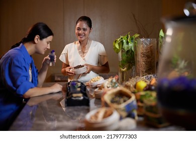 Young Caucasian Woman Drinking Healthy Herbal Tea Before Beauty Procedures In Luxury Spa Salon. Therapist Is Serving Welcome Drink To Female Customer