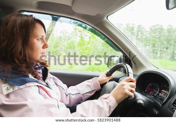Young\
Caucasian woman drives a car at summer\
day