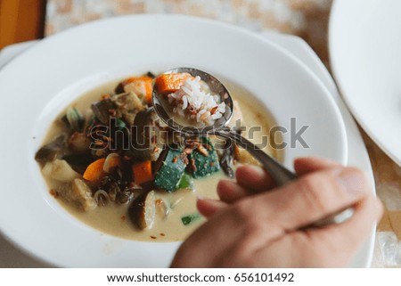 Young caucasian woman eating vegetarian curry dish served for lunch in asian cafe during vacation retreat