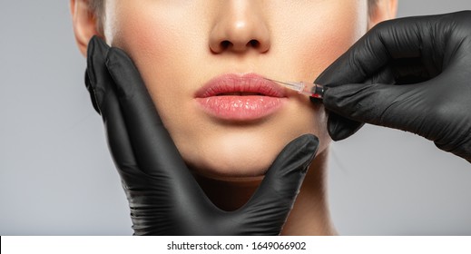 Young caucasian woman getting botox cosmetic injection in the lips. Beautiful woman gets botox injection in her face. Adult girl gets cosmetic injection of botox in a clinic. Beauty treatments - Shutterstock ID 1649066902