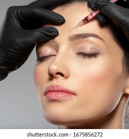 Young caucasian woman getting botox cosmetic injection in a forehead. Beautiful woman gets botox injection in her face. Adult girl gets cosmetic injection of botox in a clinic. Beauty treatments