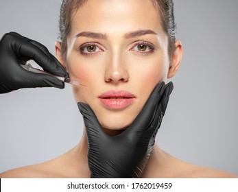 Young caucasian woman getting botox cosmetic injection near the eyes. Beautiful woman gets  injection in her face. Adult girl gets cosmetic injection of  in a clinic. Beauty treatments