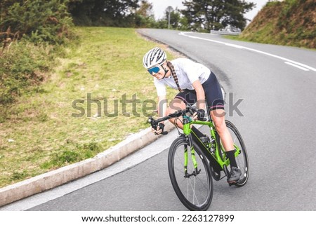 Young caucasian woman going downhill on a corner with a road bike on an asphalt road of a mountain.