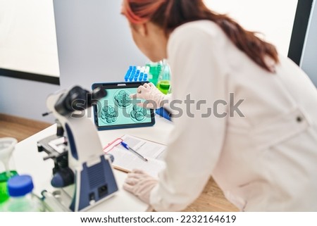 Young caucasian woman gynecologist looking embryo on touchpad at laboratory