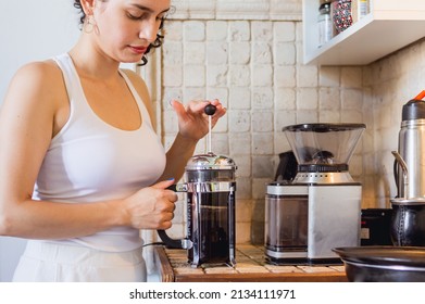 Young Caucasian Woman In Her Home Kitchen Preparing Coffee With A Manual French Press Coffee Maker On The Counter, Coffee Shop And Lifestyle Concept.