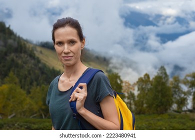 Young caucasian woman hiking in mountains with backpack, enjoying her adventure. Wide shot
