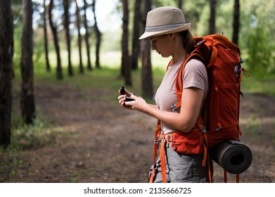 Young Caucasian Woman Is Hiking And Using A Compass In The Forest.